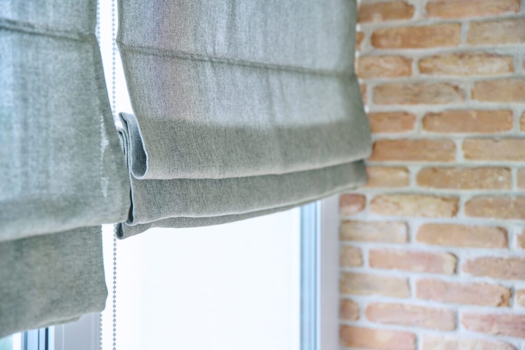 roman blinds against brick wall