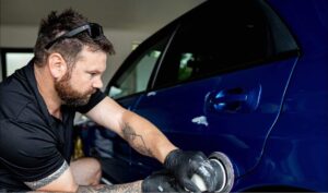 professional car detailer working on blue car