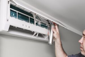 man cleaning home air conditioning unit