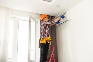 An air conditioner technician repairs a split system air conditioner in a home.