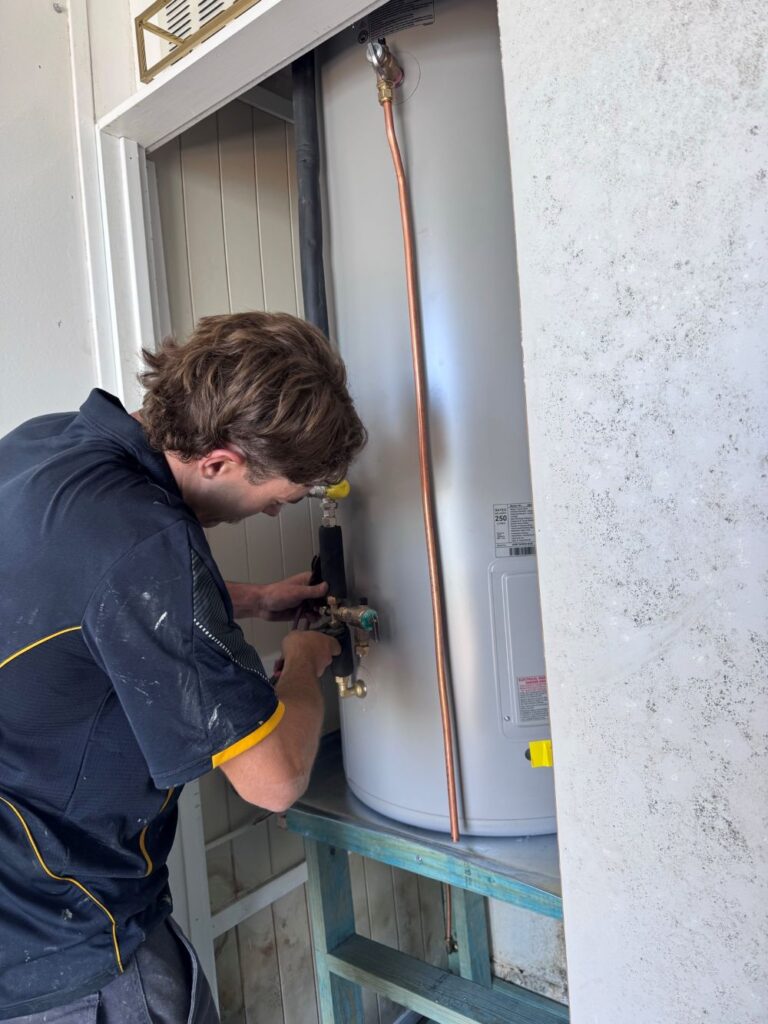 plumber working on hot water system coomera